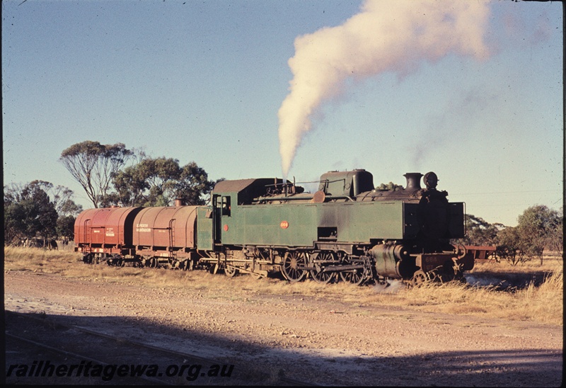 T04445
UT class 664 steam locomotive, with safety valves lifted, at southern end of Watheroo Locomotive depot. Two JA class water tankers attached to locomotive. MR line.
