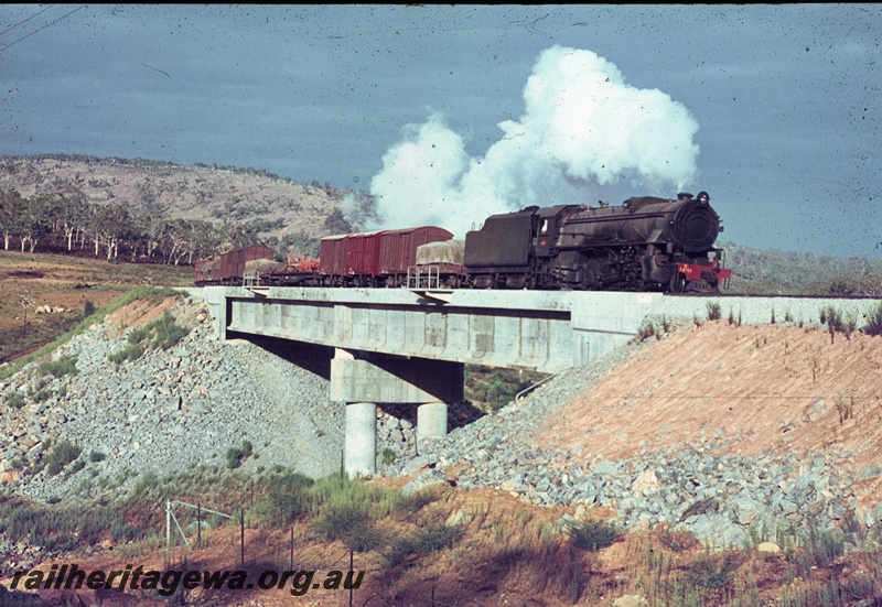 T04450
An unidentified V class steam locomotive, with a goods train, travelling over the Wooroloo Brook bridge in the Avon Valley enroute to Midland. ER line.
