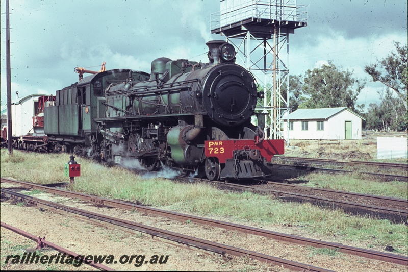 T04452
PMR class 723 steam locomotive, hauling a goods train, pictured at Pinjarra. Water tower visible to right of locomotive and shunting signal at left. SWR line.
