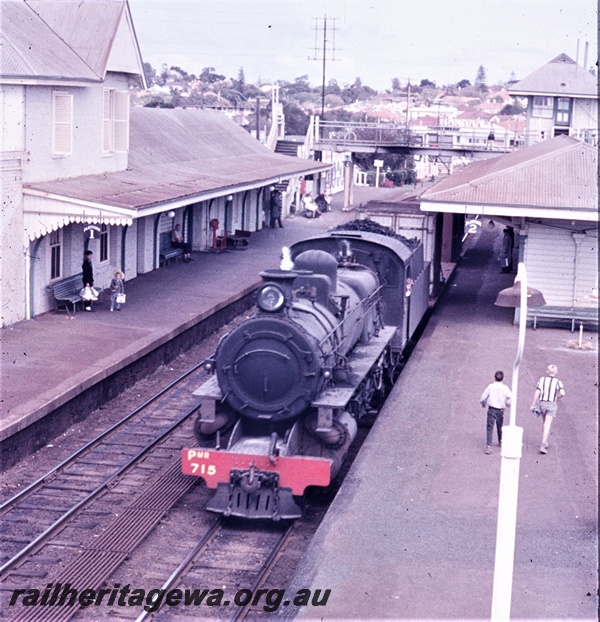 T04605
PM class 715 steam locomotive with a goods train, station buildings, footbridge and signal box in the background, Claremont, ER line, elevated view looking west. 
