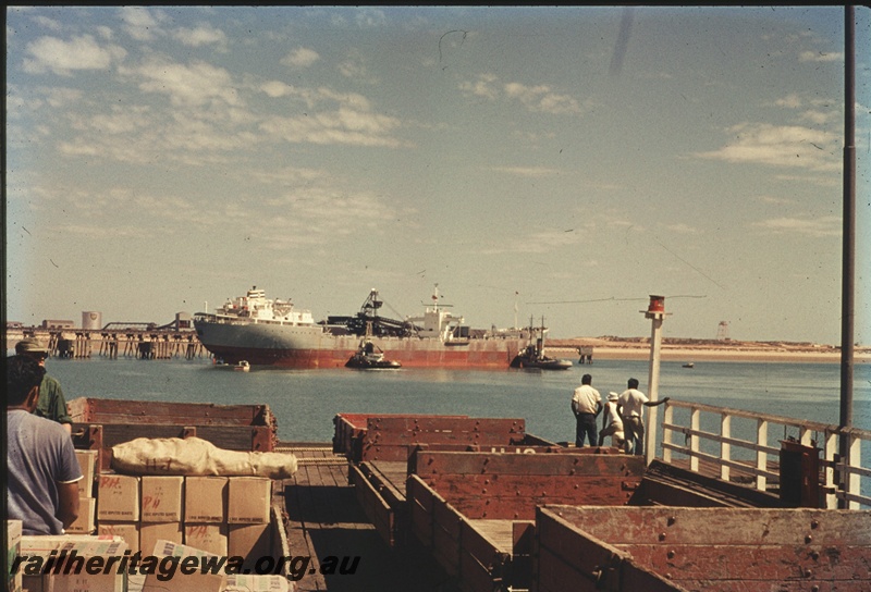 T04631
An early iron ore ship at Port Hedland being loaded with ore. In the foreground is the former Port Hedland Jetty with empty and part loaded wagons.
