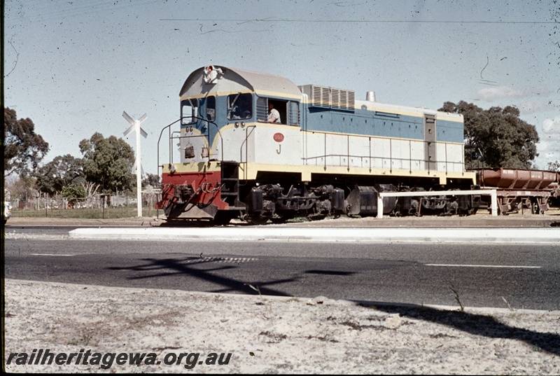 T04645
J class 101 standard gauge diesel locomotive with a rake ballast train of 4 wheeled wagons traversing a level crossing at Kenwick. 
