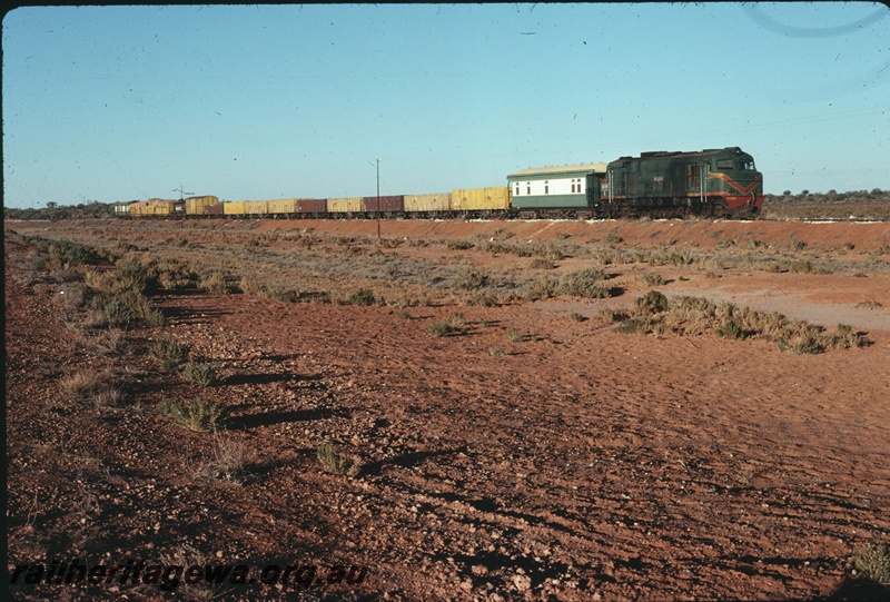 T04684
An unidentified X class diesel locomotive on a goods train at 380km point on the Meekatharra - Mullewa railway. The vehicle behind the locomotive is possibly a district inspection car.
