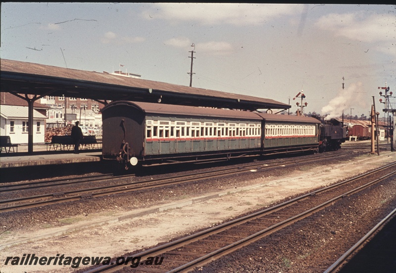 T04726
An unidentified DD class steam locomotive with two suburban side door carriages in the green and white with a red stripe livery  departing Perth Station.
