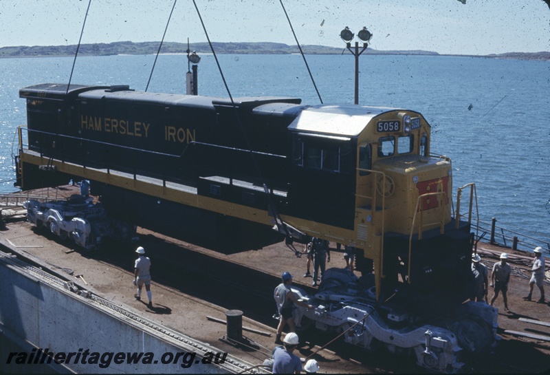T04774
Hamersley Iron (HI) GE36-7 class 5058 (Goninan-GE) being lifted onto wharf from vessel MV Iron Baron at Dampier. 
