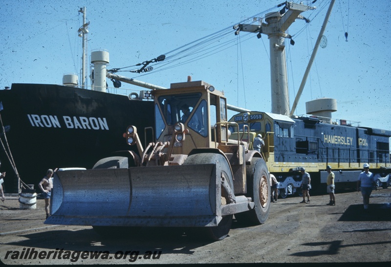 T04780
Hamersley Iron (HI) GE36-7 class 5059 on wharf at Dampier being towed by large bulldozer.
