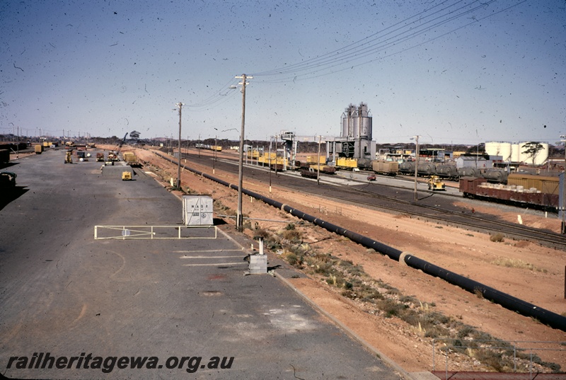 T04903
View of yard, narrow gauge gantry area, crane, loading ramp, standard gauge nickel bins, various wagons, motor vehicles, West Kalgoorlie, EGR line
