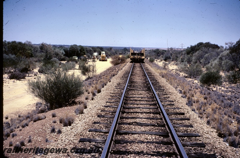 T04906
Wagon loaded with rails, awaiting units, workers, road vehicles, between Burracoppin and Carrabin, EGR line
