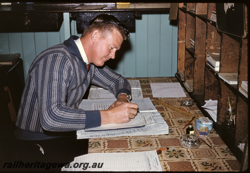 T04919
Ken Ashby, station master, busy with the ledgers, interior view of office, Tambellup, GSR line.
