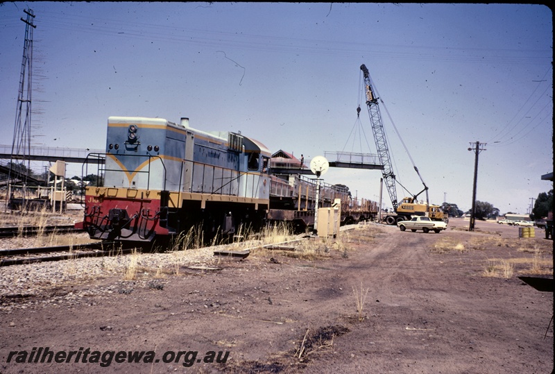 T04927
J class 104, in light and dark blue livery with yellow stripe, on works train, during removal of old footbridge, worker, station building, signal box, Keogh mobile road crane, Merredin, EGR line 
