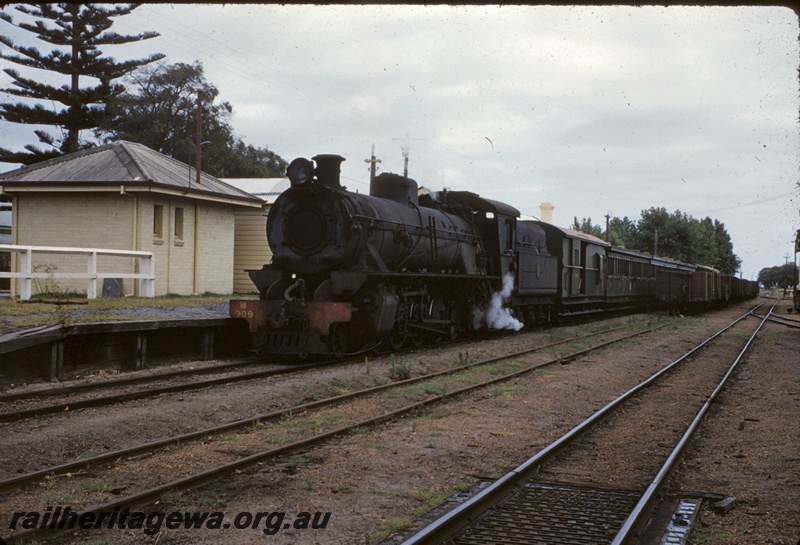 T04989
W class 909, on passenger train, rake of goods wagons, platform, country station building, points, siding, Busselton, BB line, front and side view
