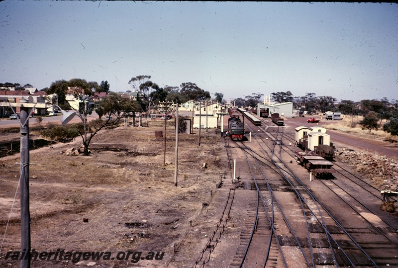 T05037
Station yard, X class diesel in green livery, wagons, vans, signals, bracket signals, points, water column, platform, station buildings, shops, goods shed, Goomalling, EM line
