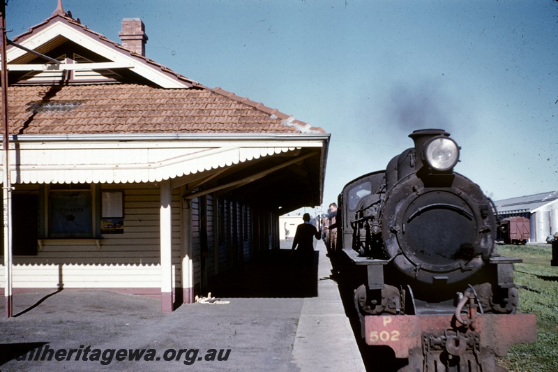 T05163
P class 502, as staff being exchanged, on special goods train to Katanning, platform, station building, van, wheat bin, Tambellup, GSR line, platform level view
