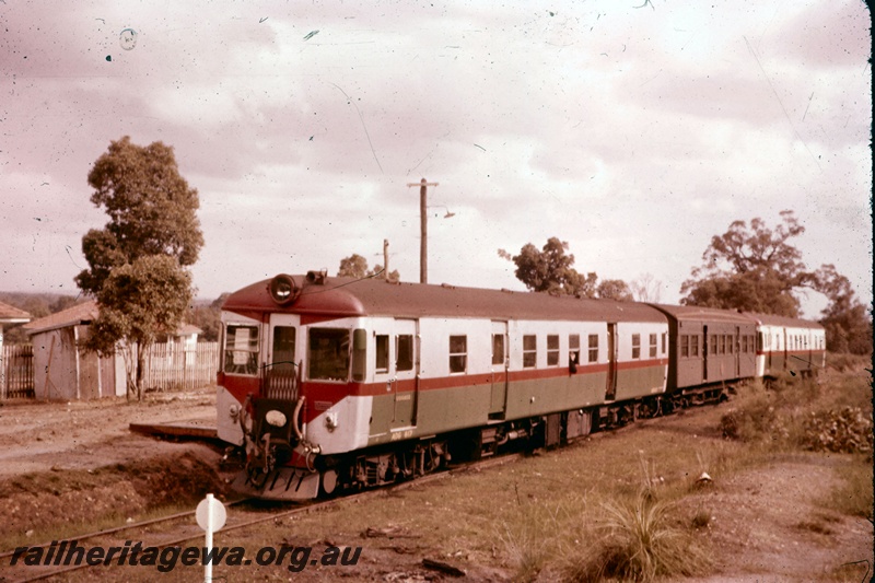 T05207
ADG class 617 as the trailing unit of a three car set, the centre unit being an AYE class railcar trailer carriage in the plain green livery, shed, fence, platform edge, the white disc on a pole is one of a series of discs which indicate the stopping point for various lengths of trains, Koongamia, M line, front and side view, tail disc on the end of the railcar
