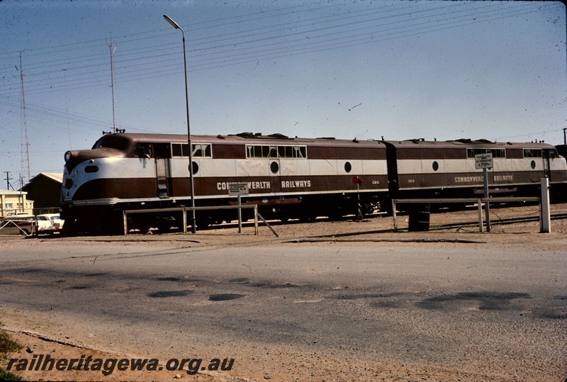 T05231
Commonwealth Railways (CR) GM1 class 4 and Commonwealth Railways (CR) GM1 class 8, in maroon and silver livery, coupled back to back, level crossing, Pt Augusta, TAR line, front and side view 
