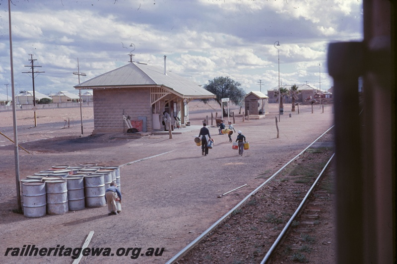 T05243
Station building, point levers, houses, children handling drums, Rawlinna, TAR line, photo taken from train
