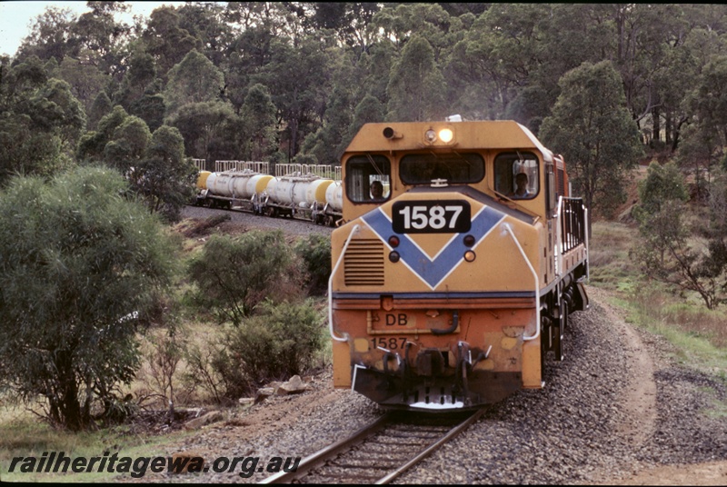 T05279
2 of 2 views of Westrail DB class 1587 in the orange livery with the blue stripe and the loco's number on the front within a black rectangle double heading with another DB class on a Caustic train of JK class tank wagons, mainly a head on view of the loco
