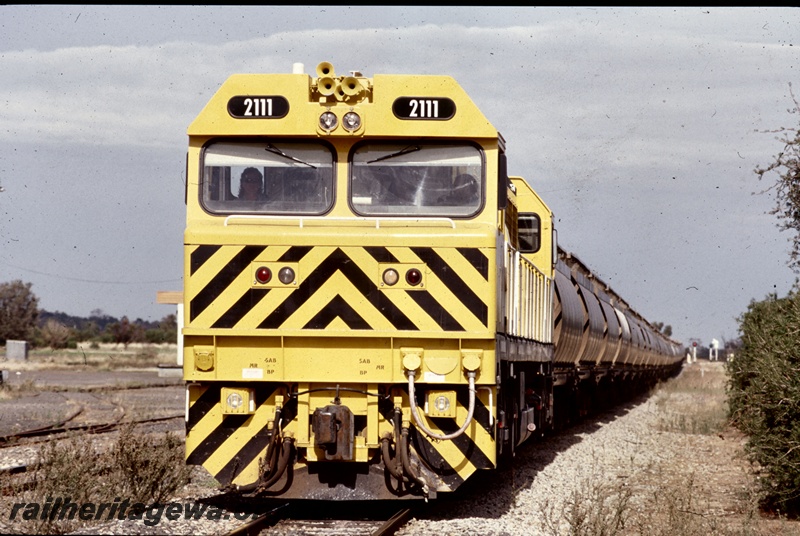 T05285
1 of 2 views of Westrail S class 2111 in the yellow livery with black chevrons on the front end hauling an alumina train of XF class wagons at Brunswick Junction, SWR line, front on view 
