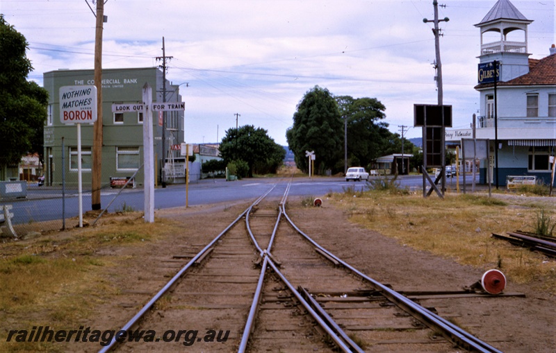 T05443
Rail tracks across Great Eastern Highway, points, red faced cheeseknobs,  The Commercial Bank building, motor car, rail crossing sign, view looking east from the Midland Railway Co (MRWA) yard, Midland, MR line, view from trackside
