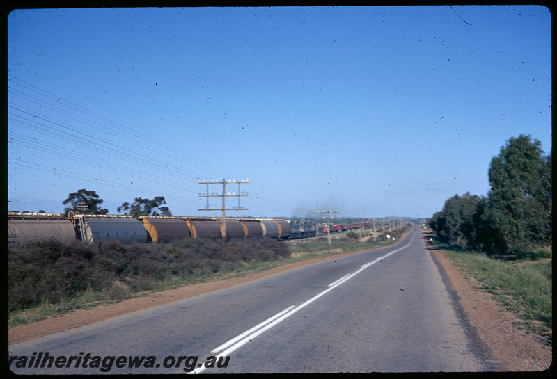 T06257
Unidentified double headed L Class on standard gauge grain train, passing A Class 1504 on goods train on old narrow gauge EGR line running parallel to new standard gauge line, east of Kellerberrin, Great Eastern Highway in foreground, WW Class 32006 grain wagon, WWA Class grain wagon
